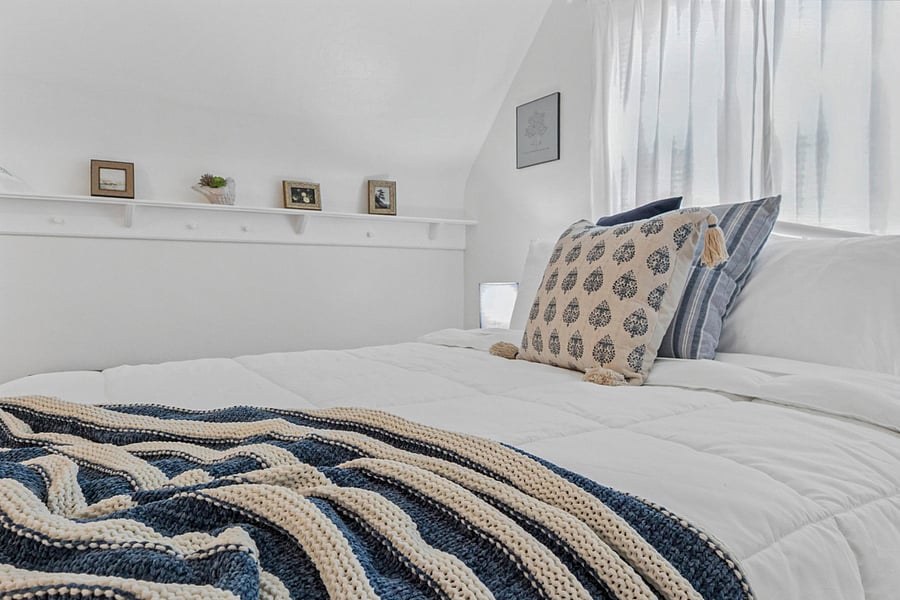 Soft textures and inviting layersour upstairs queen bed at the South Bend guest retreat features a cozy throw and plush bedding, perfect for restful nights near Notre Dame.