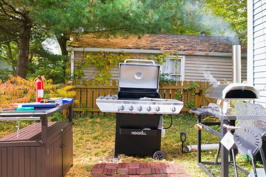 Grill, prep, and fire up flavorour South Bend guest retreat features a 5-burner propane grill, backyard pizza oven, and prep table for alfresco meals and family-friendly fun near Notre Dame.