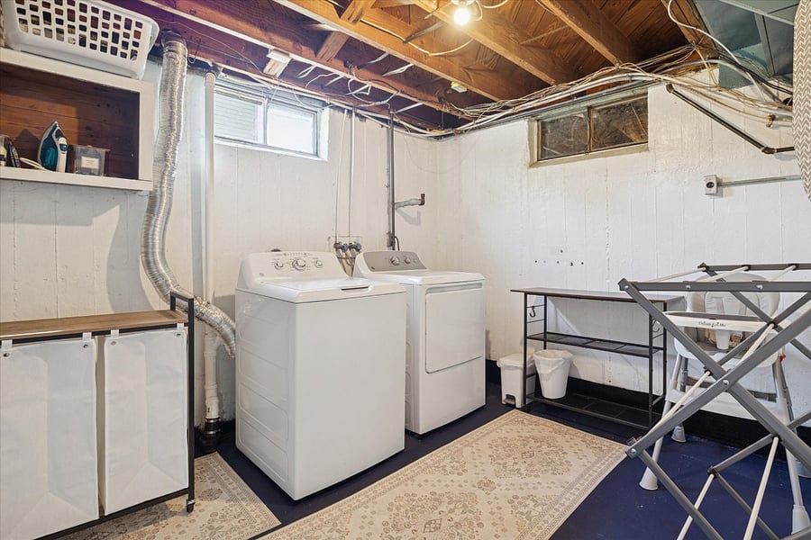 Fresh, functional, and family-readyour South Bend guest retreat laundry room features oversized machines, drying rack, folding table, baskets, bins, dryer balls, and laundry pods for easy upkeep