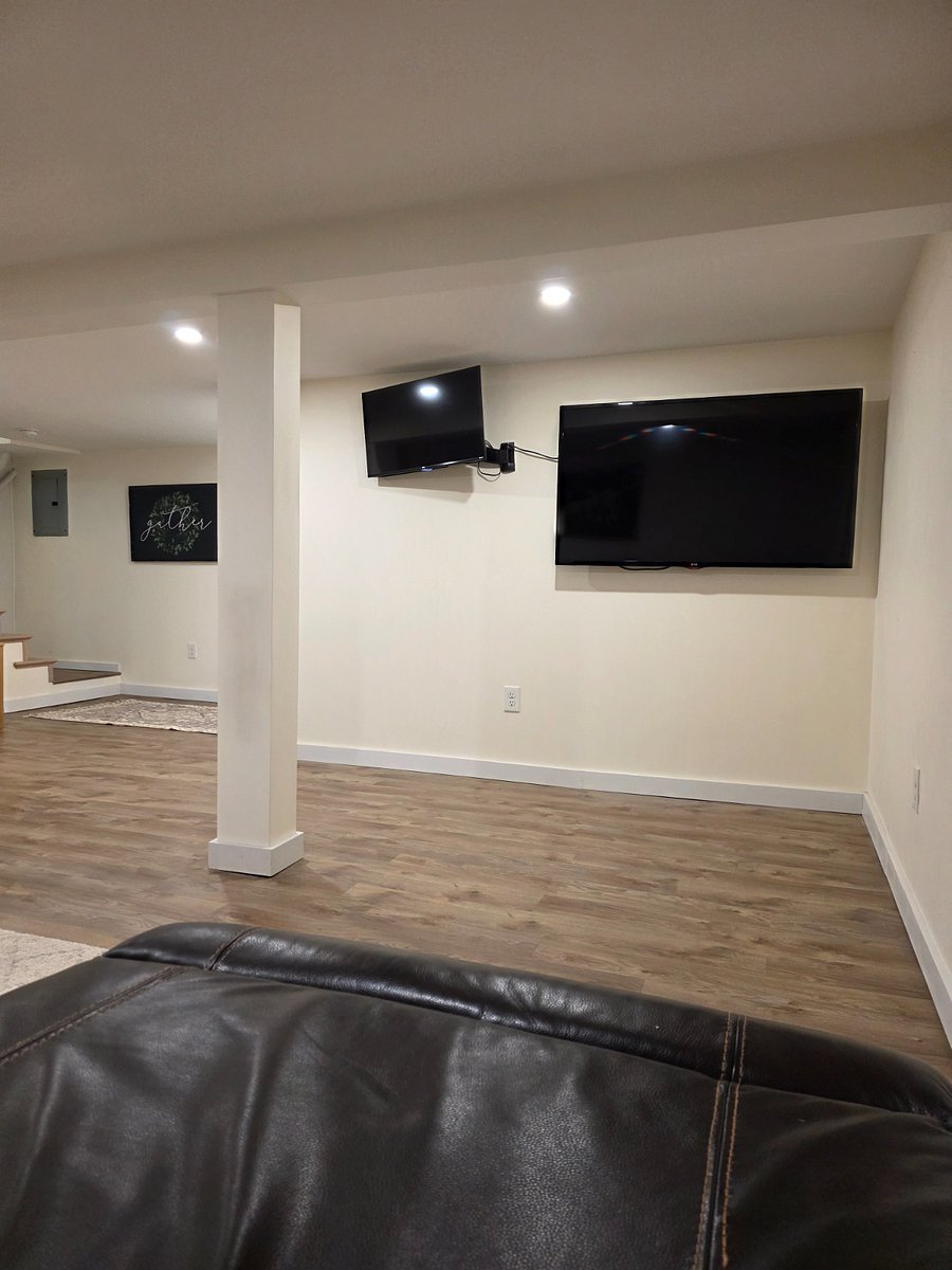 View of 2 basement TV's from large electric reclining leather couch sectional