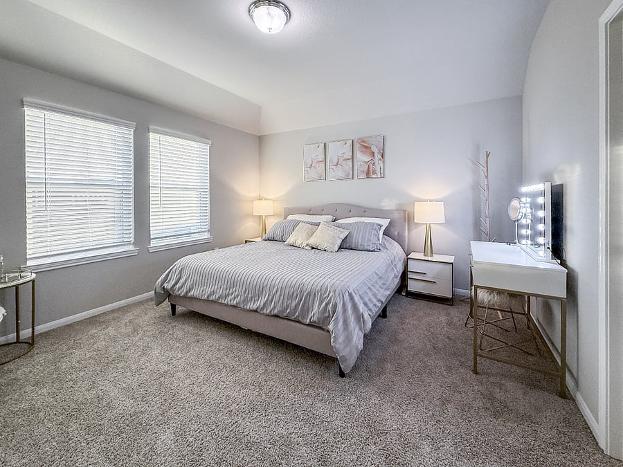 Bright master bedroom with a king bed, soft bedding, and calming dcor. Includes a vanity area and plenty of space to relax and recharge.