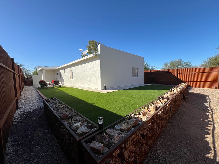 Side yard and back yard featuring artificial turf and privacy fence.
