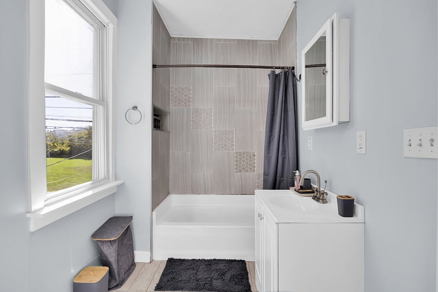 Modern bathroom with fresh towels, full shower, and starter toiletries provided.