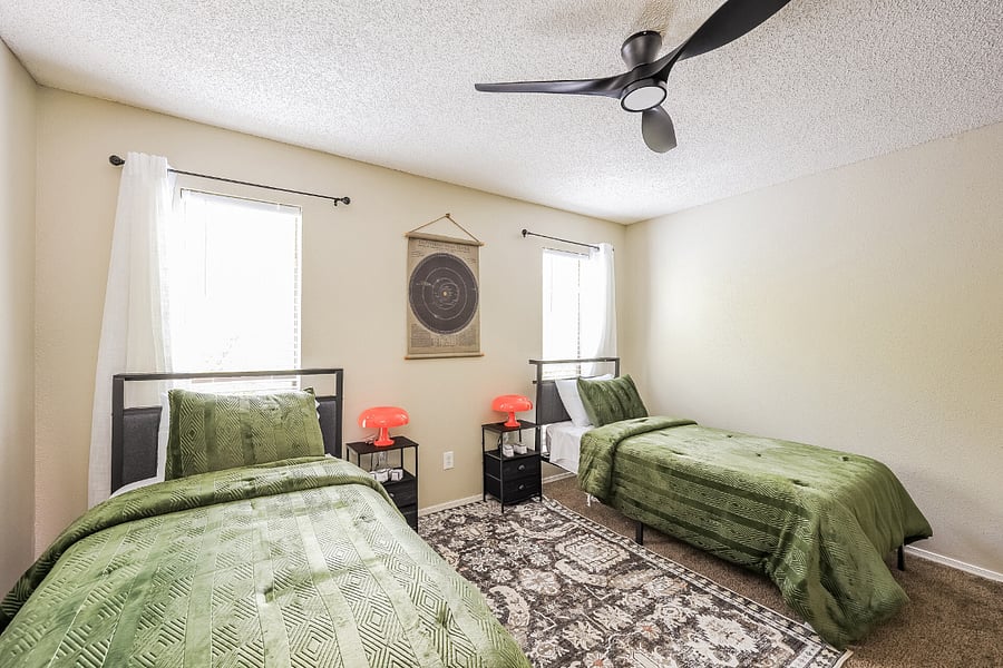 Second bedroom with two twin beds and a dedicated desk, suitable for a colleague, kids, or work-from-home setup.