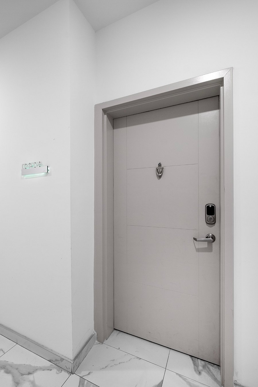 Sleek, modern white door set in a minimalist white wall. The door is equipped with a digital keypad lock and a peephole, emphasizing security and convenience.