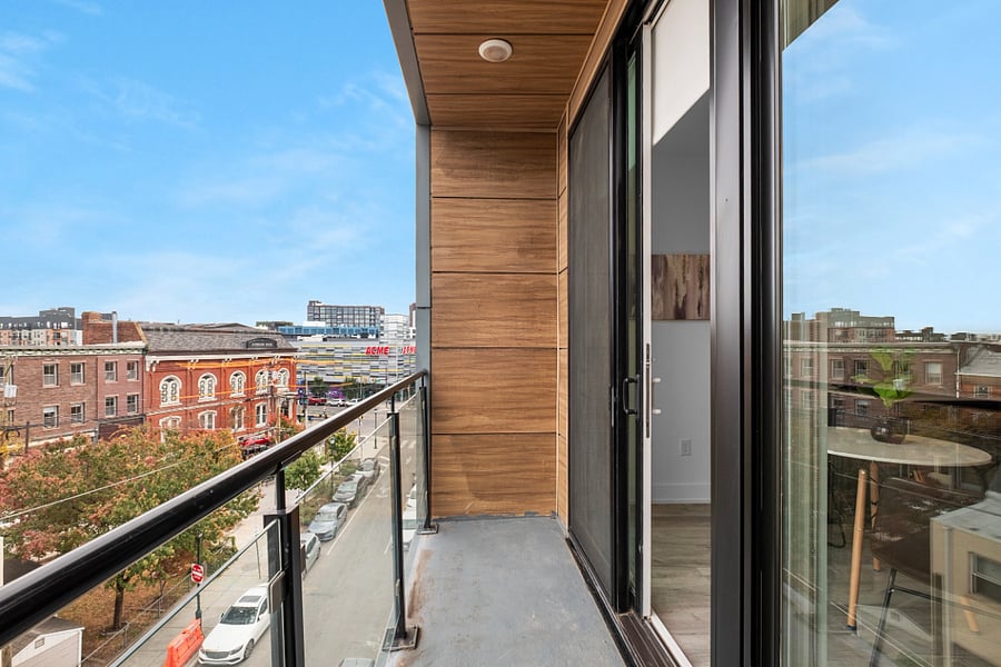 a stylish urban apartment view from a balcony with glass railing and wood-paneled walls.