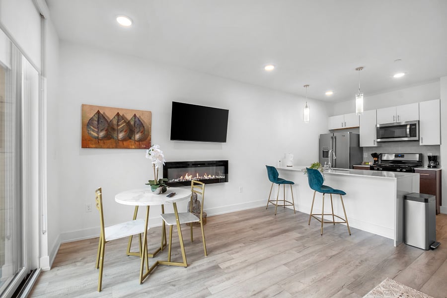 A sleek, modern kitchen with a white quartz island featuring a built-in sink and two elegant blue quilted bar stools. 