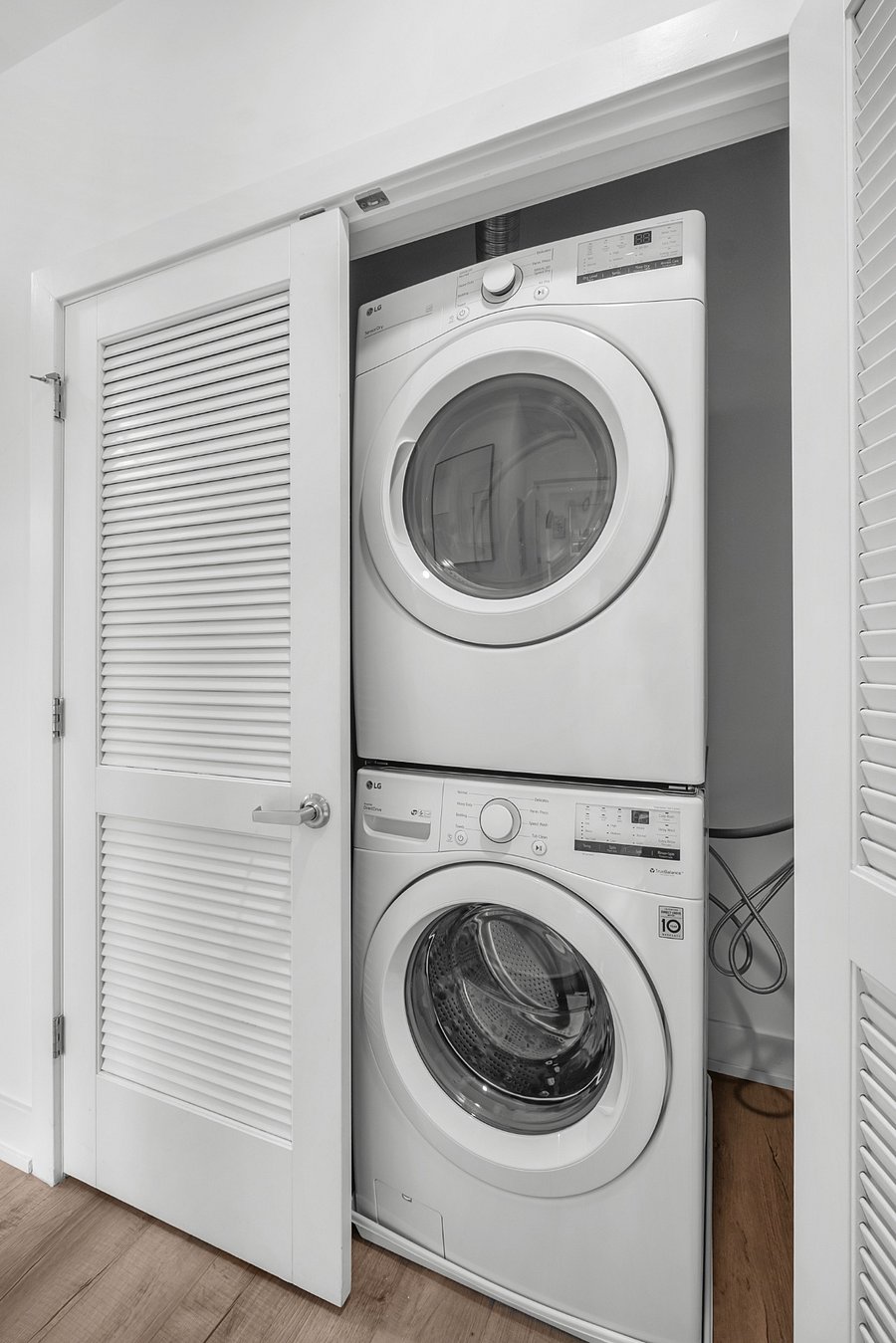 A stacked front-loading washer and dryer tucked neatly into a small closet. 