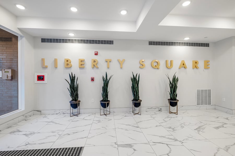 Elegant lobby features a clean white interior with marble-like tile flooring and recessed lighting.