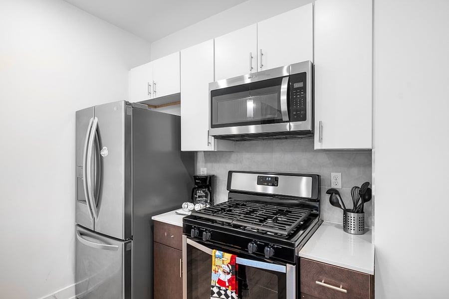 A sleek, modern kitchen with a white quartz island featuring a built-in sink and two elegant blue quilted bar stools. 