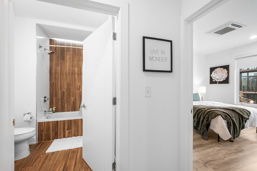 Hallway view leading to a bathroom on the left and a bedroom on the right.