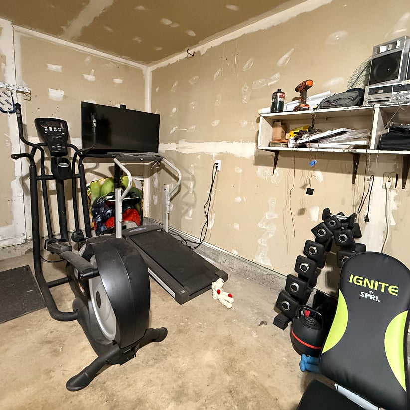 Garage gym equipped with treadmill, elliptical, kettlebells, dumbbells, and bench for your personal workouts.