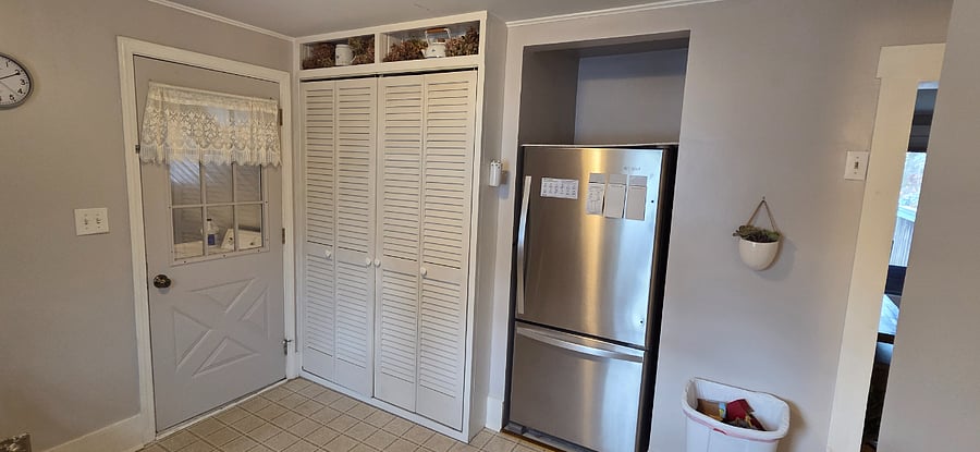 Kitchen has full-sized refrigerator with pantry cupboards. Door to entry room with storage and washer and dryer.