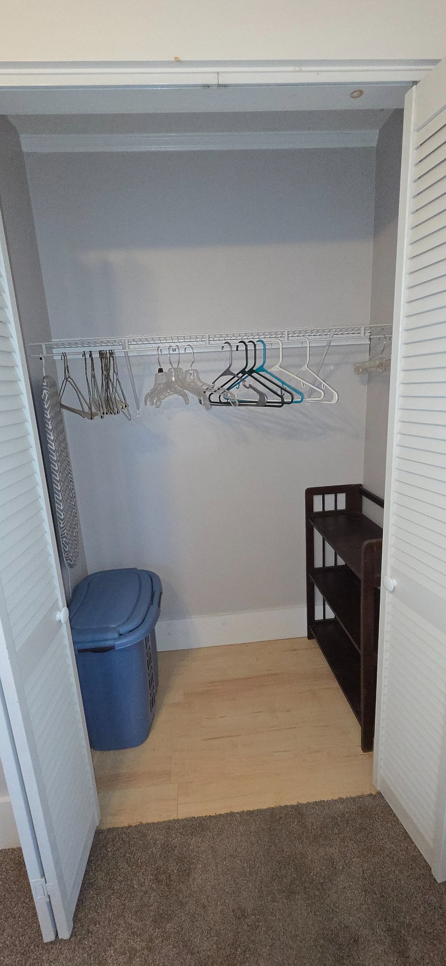 Bedroom closet with shoe rack, hamper, shelf and hangers.