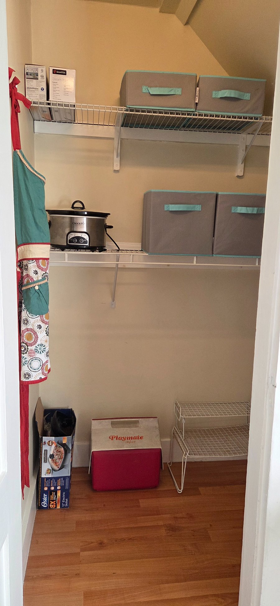 Office room has a walk-in closet with extra bed linens, ironing board, iron, crock pot, cooler, electric fry pan, extra dishes, apron and extra storage bins.