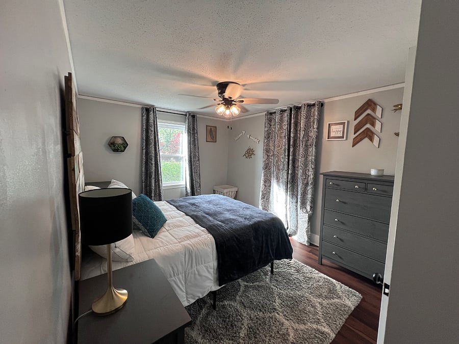 Bedroom 1 with queen bed, 1 closet, dressers, and blackout curtains. 