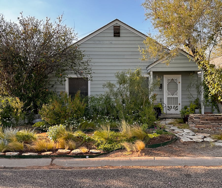 Front of cottage with small porch and drought-tolerant garden, this photo features late summer/fall plantings.
