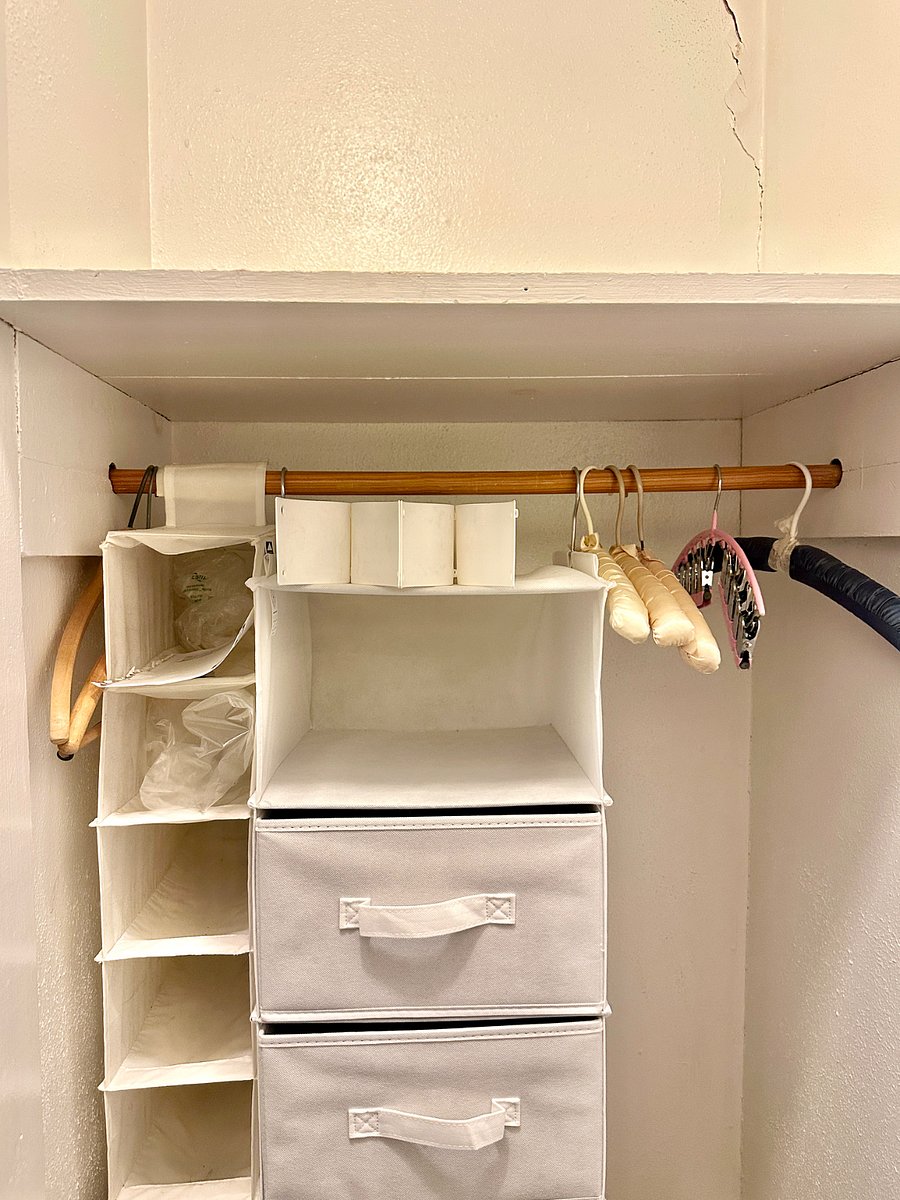 Bedroom closet left side with a big shelf above. Right side has three to four shelves available. Additional shelves outside of closet behind curtain.