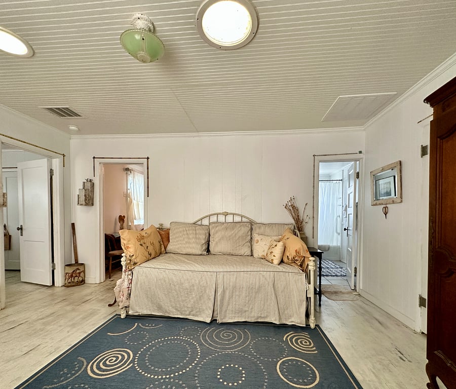 View from the front door showing doors to the bedroom (left), the kitchen (middle), and the bath (right). Smart TV/media armoire, 2 skylights, daybed with pop-up trundle.
