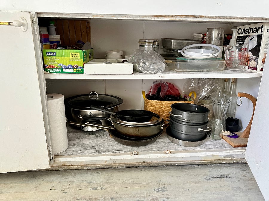 Lower kitchen cabinet items include crockpot, blender, pots and pans, silverware, tools, and vases.