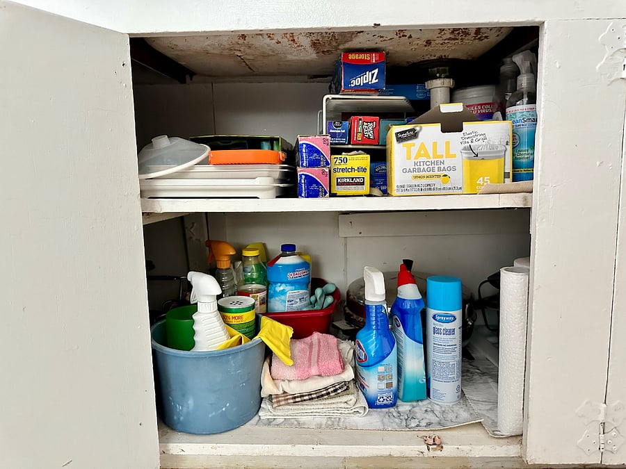 Cabinet under the sink includes cleaning supplies, microwave tools, and food storage. 
