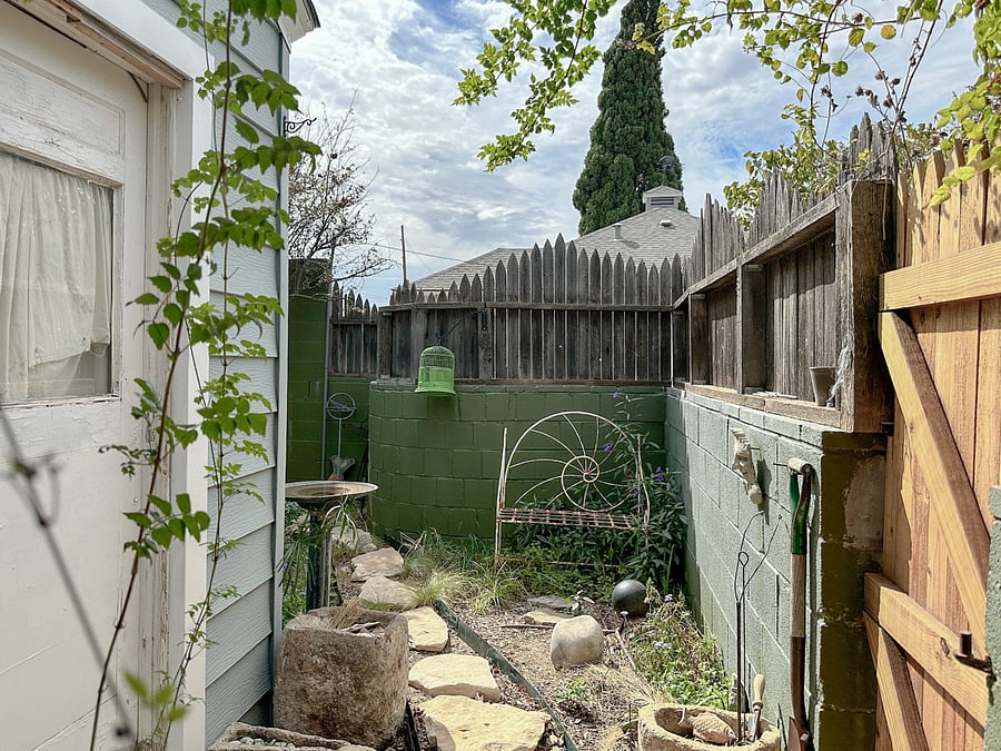 Tiny private, fenced-in garden includes bench, birdbath, edible plants, and cut flowers. Cushion for bench in a closet. The path leads to the small space for the AC unit.