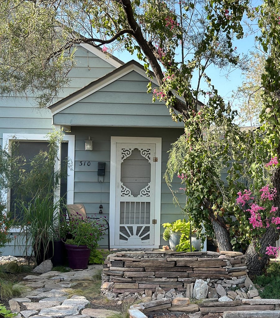 Front porch with summer/fall blooming Queen's wreath vine by the stacked rock planter space. Nice space for coffee or relaxing with a book or your phone. You're invisible while in plain sight.