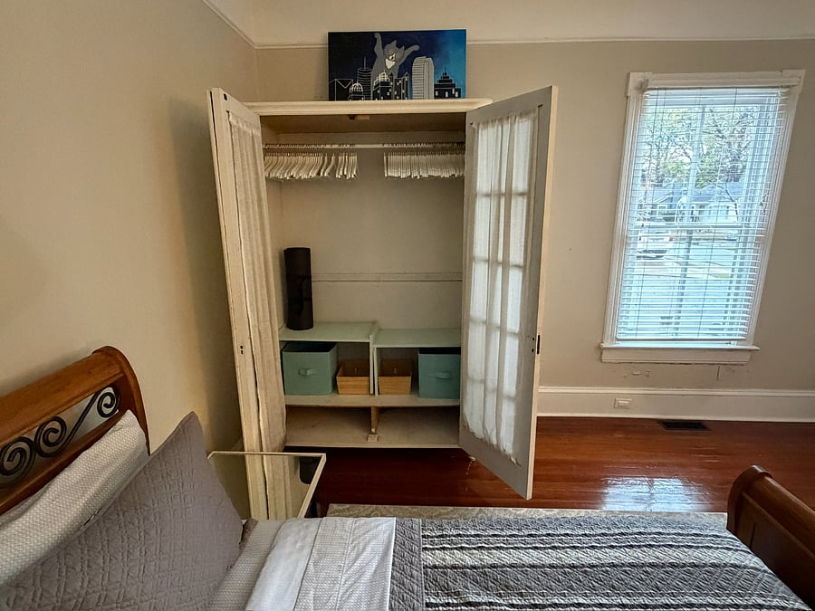 Armoire with doors open showing hanging and storage spaces.