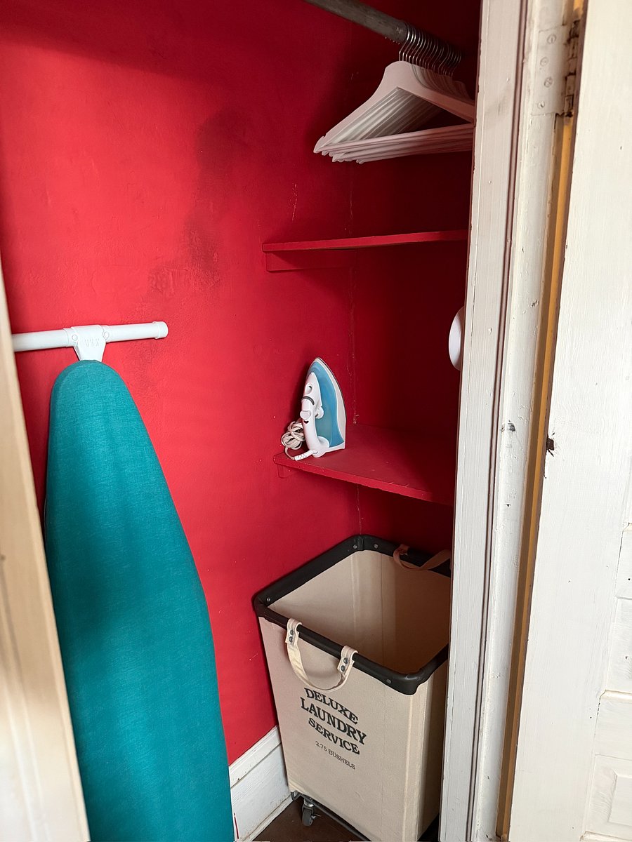 Closet housing additional hangers, ironing board + iron, and (2) laundry baskets on wheels.