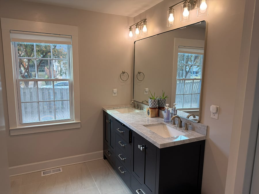 Newly renovated bathroom featuring double vanity and oversized mirror.