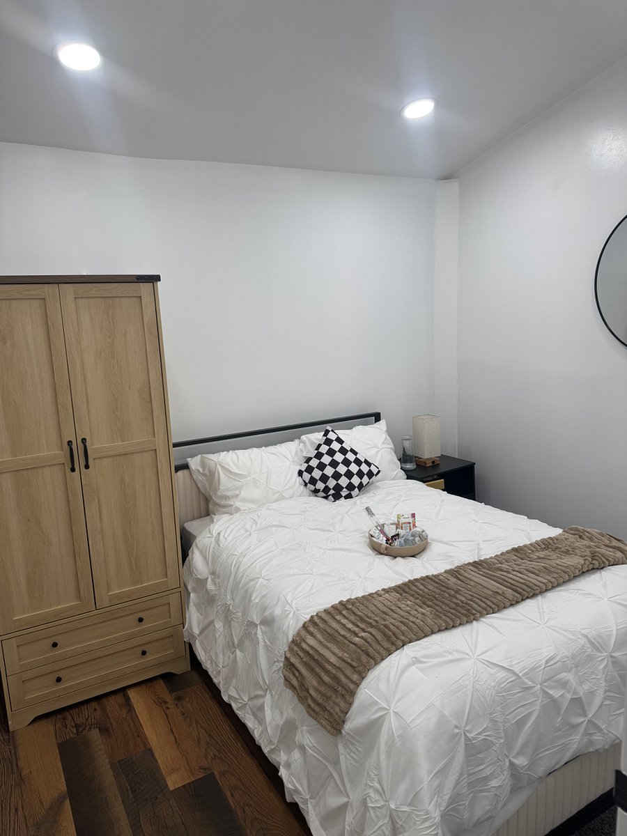 Bedroom with plush bedding, night stand, and armoire for clothing storage