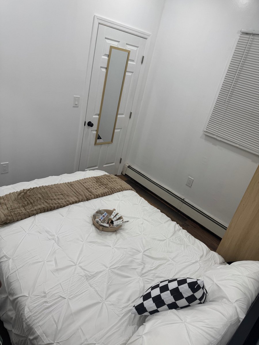 Bedroom with plush bedding, night stand, and armoire for clothing storage