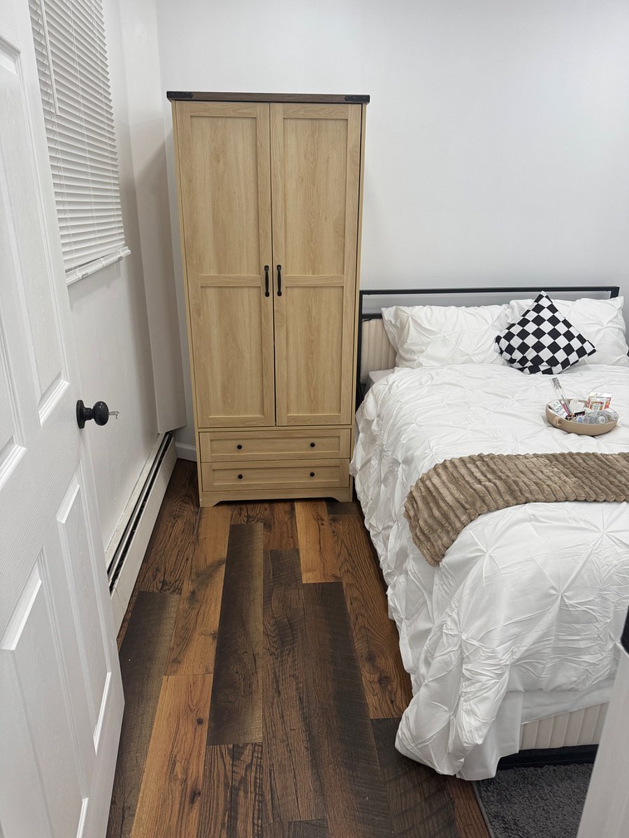 Bedroom with plush bedding, night stand, and armoire for clothing storage