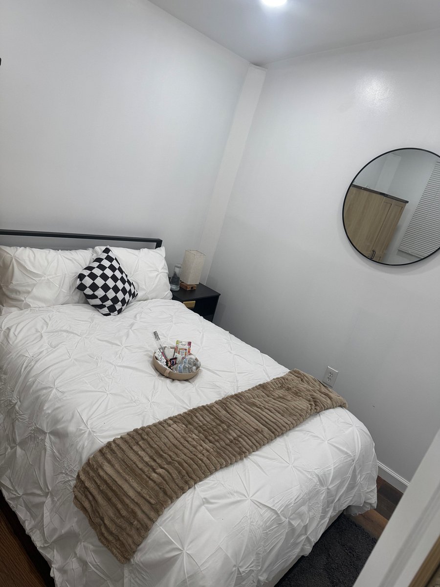 Bedroom with plush bedding, night stand, and armoire for clothing storage