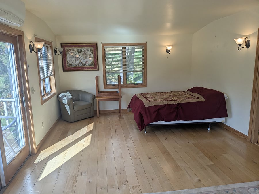 Upstairs Large Bedroom. Slider leads to small deck 6x12. Lovely views of property from this deck.Note bove sliding door to deck a new Mitsubishi combo heat/ac heat pump installed. This large room gives TENANT THE CHOICE of either heat from heat pump or from Rinnai.
