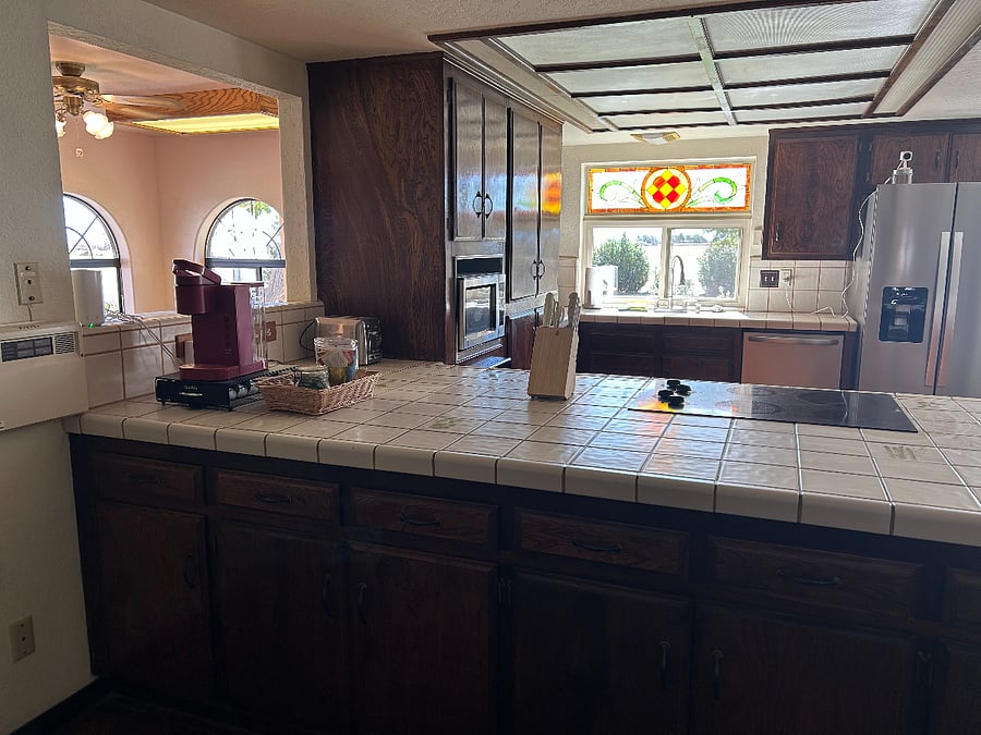 Well-stocked kitchen with hand painted tiles on the counter top.and an abundance of storage space.