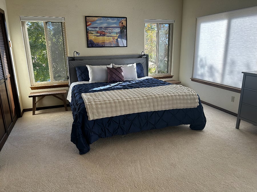 Master bedroom with king size bed, lots of windows, storage space, extra charging stations and sitting room with a TV