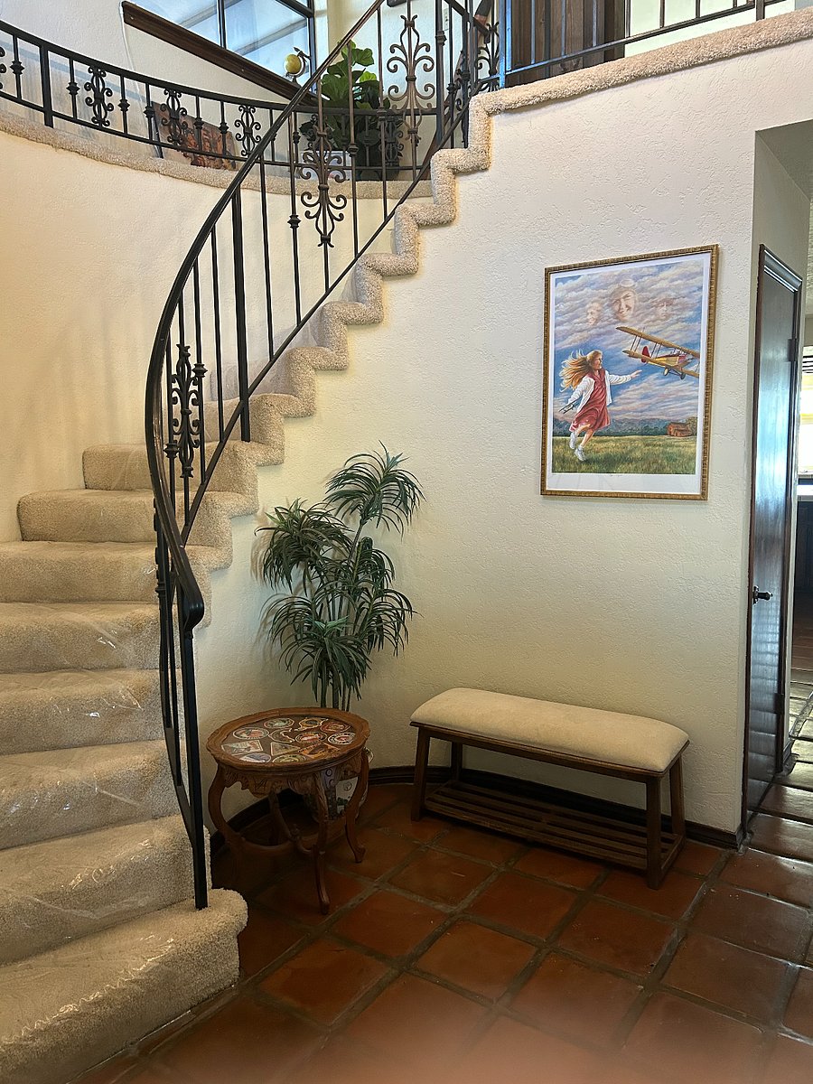 Entry Hall with access to the stairs and a guest bathroom with bench, antique table, and a signed lithograph.