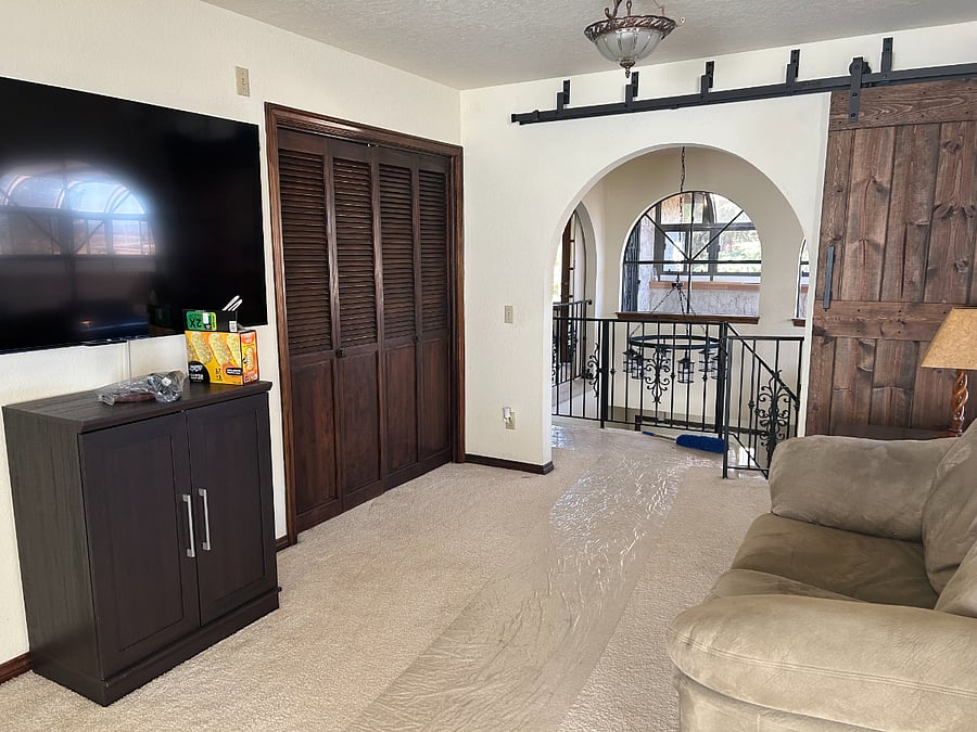 Master bedroom with sitting area, large TV, charging station, storage space, and access to the stairs..