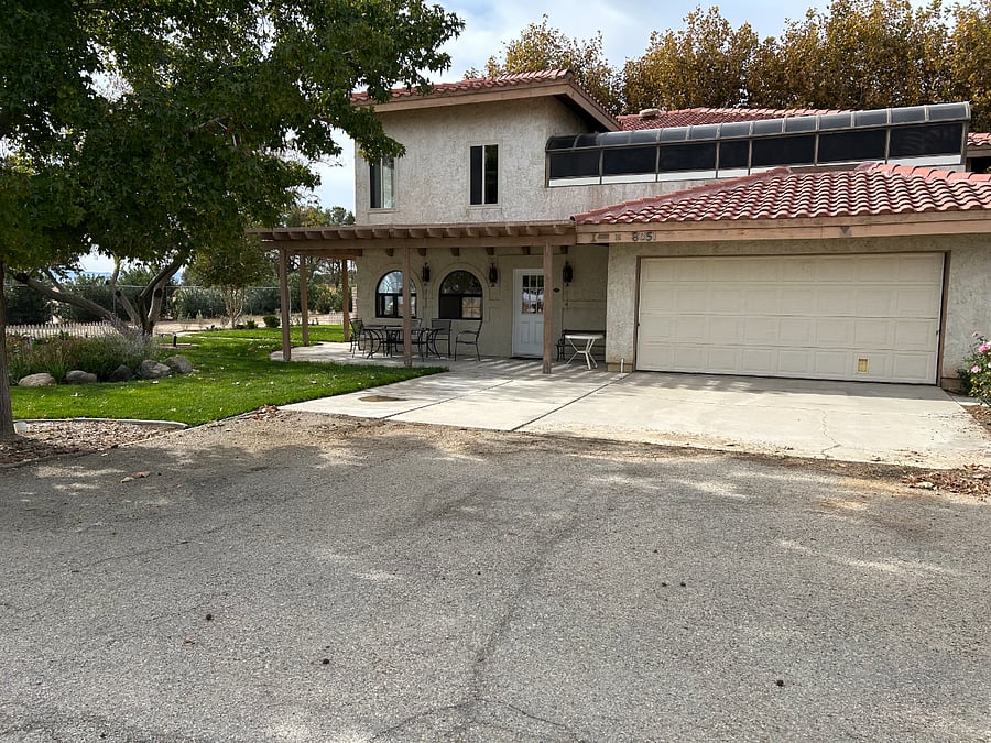 Side entrance with access to the 2-car garage which has an entry into the enclosed patio. Outside area with table, chairs, and barbeque. 2nd floor solarium is visible over the garage.