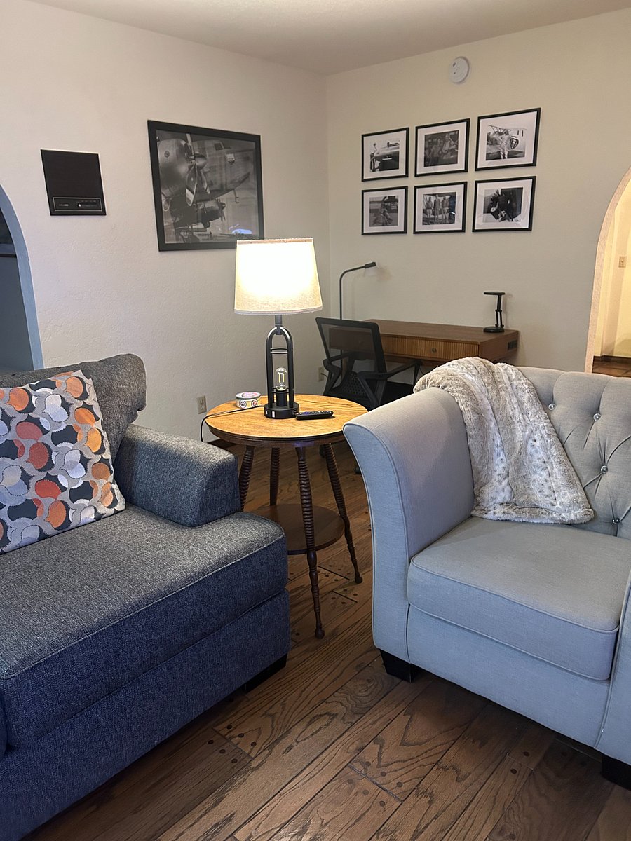 The living room features a desk, comfortable chair, a plug in for a computer.