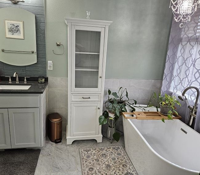 Master bath includes extra deep tub situated next to window for plenty of natural light and mini chandelier above the tub.