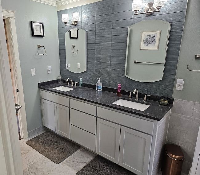 Master suite includes master bathroom with twin vanities, marble floors and gray subway tile backsplash.