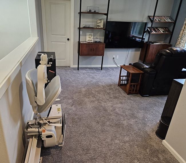 The house is equipped with a powered stair chair lift with max capacity of 300 lbs.  The bedroom door is just beyond the chair lift to the left of the standing cabinet.