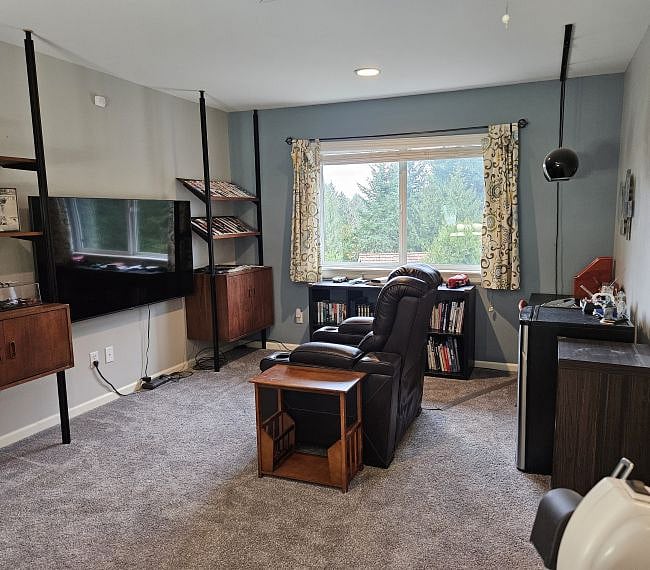To the right of the window, behind the recliner, is a small refrigerator and work table.