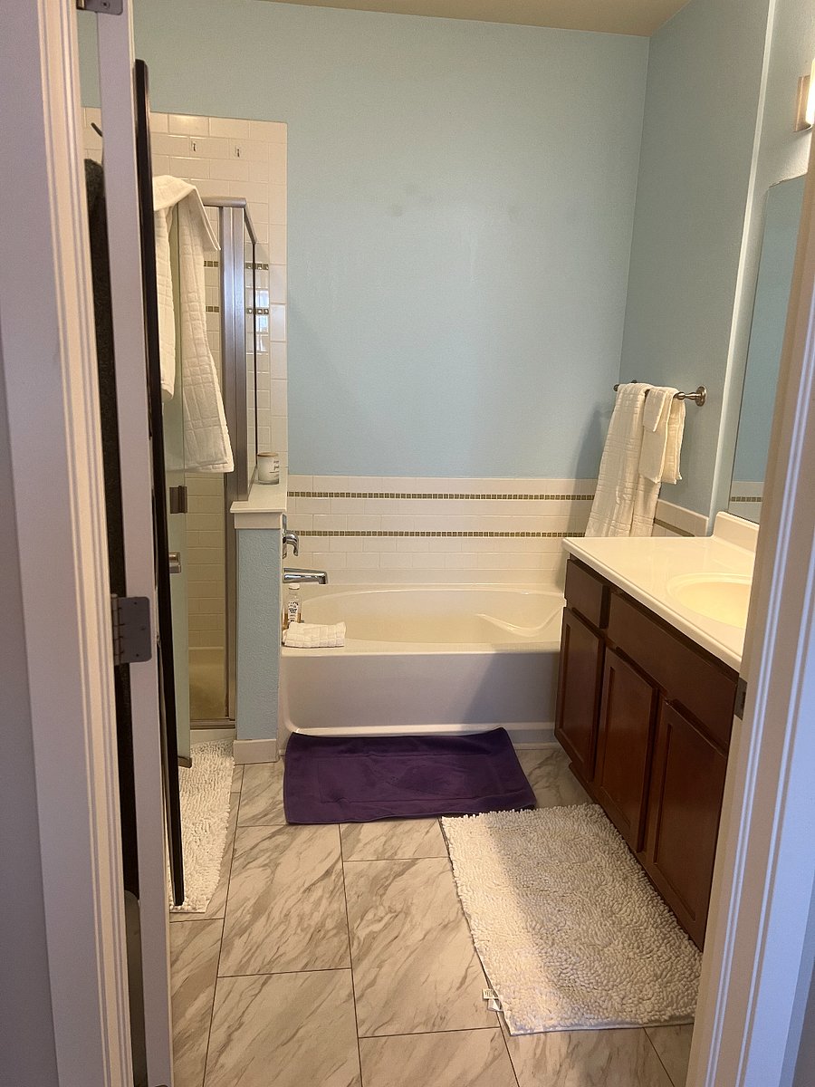 Master bath with full sized tub, shower, towel, and sink.