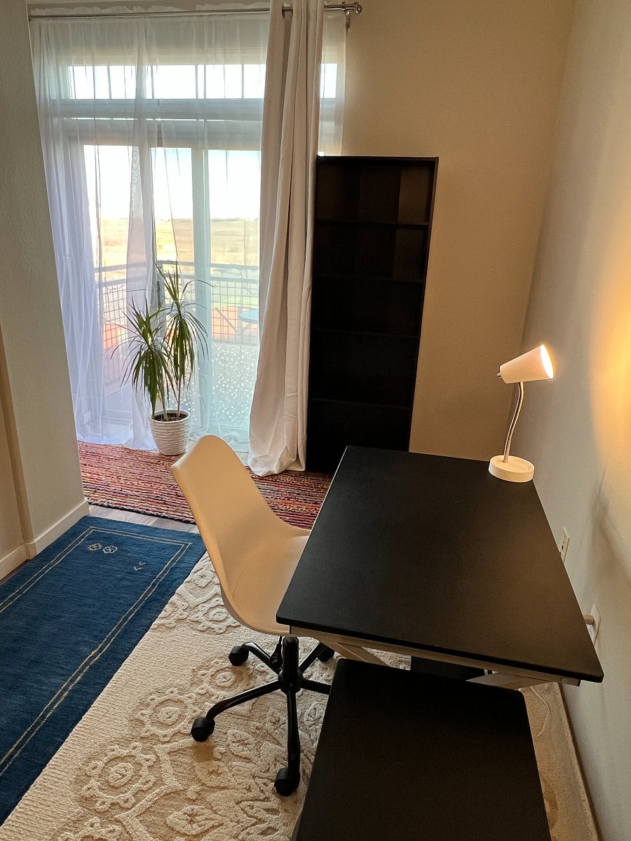 Office space with desk and rolling adjustable height chair. Large bookshelf.