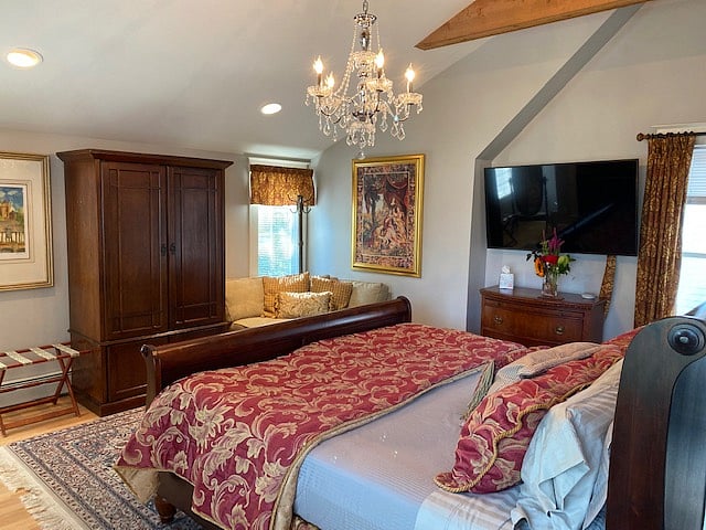 Primary bedroom featuring organic cotton king mattress, wood armoire for your hanging garments, bachelor's chest and large smart tv.