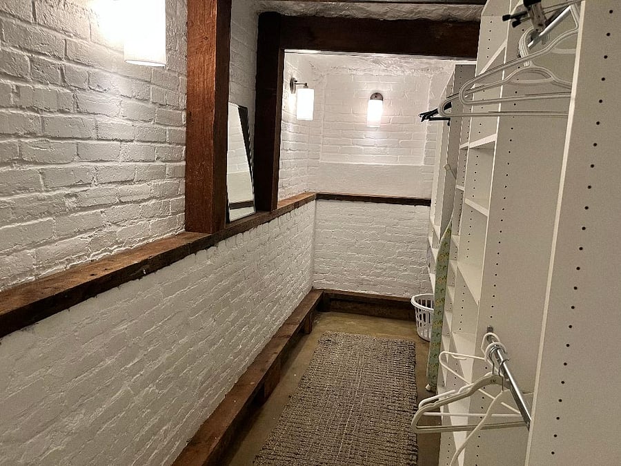 Large walk-in master closet with exposed beams and brick.