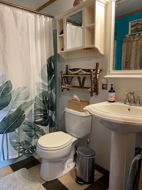 Full bathroom. A rain showerhead and tub combo are behind the curtain.